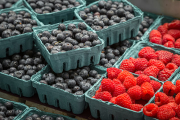 Punnets of raspberries and blueberries for sale on a market stall