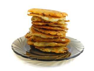 Stack of crispy fried potato pancakes on brown glass plate isolated on white background. Traditional ukrainian dish Deruni.