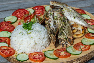 White rice with seafood and vegetables, close up . Fish, squid, shrimp, rice, tomato and cucumber in the restaurant on the island of Zanzibar, Tanzania, Africa