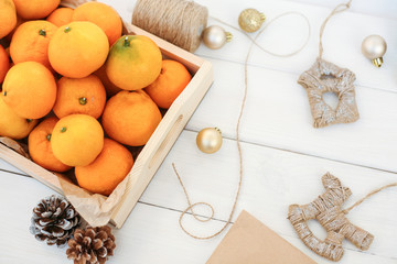 Christmas composition with tangerines (oranges, Clementines, citrus) on a white wooden background. Cones, Christmas toys, box of mandarins doing the festive mood, the space for copy