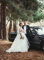 Bride and groom at wedding in nature green forest near vintage car. Photo portrait. Wedding Day