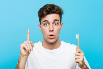 Young caucasian man holding a toothbrush Young indian woman wearing a pajamas and sleep mask isolated holding a pillow having some great idea, concept of creativity.< mixto >