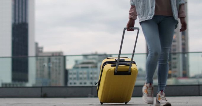 Beautiful young woman with bright suitcase outdoors