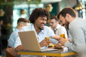 Fototapeta premium Young businessmen siting pub and drinking beer as they work