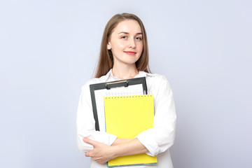 Beautiful girl student with notebooks. Concept of education. Portrait, grey background, copy space, slogan, toned
