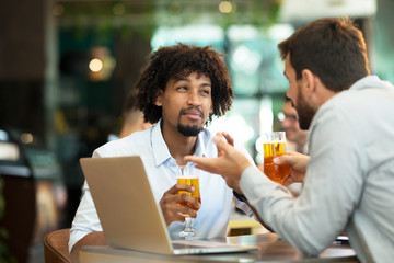 Young businessmen siting pub and drinking beer as they work
