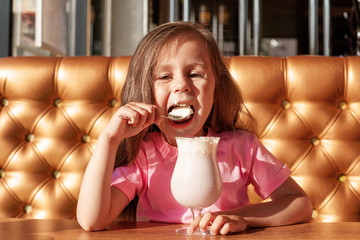 Little girl drinks milk cocktail in a cafe