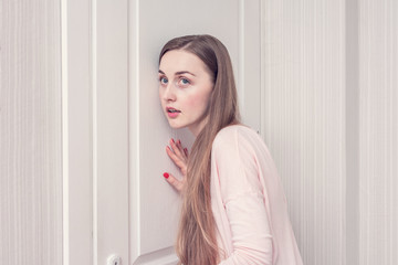 Beautiful girl overhears outside the door, portrait, close up, toned