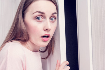 Amazed woman was listening outside the door, portrait, close up, toned
