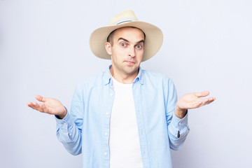 Confused cowboy in hat standing and shrugging shoulders, spreading hands, grey background,...