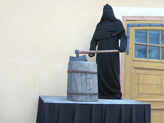 The grimmed Executioner Of The Death Penalty in black costume and mask With A Huge Sharp Ax On a...