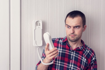 Man with intercom or phone land line, man has an unpleasant conversation, guy does not want to...