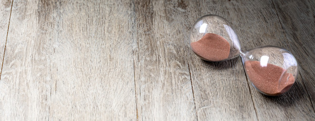 Glass hourglass lying on wooden