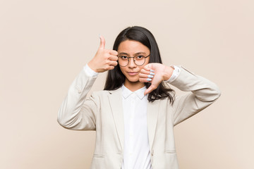 Young business chinese woman showing thumbs up and thumbs down, difficult choose concept