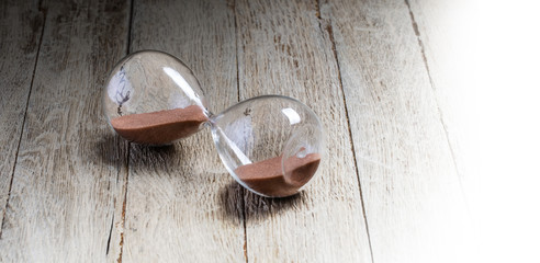 Glass hourglass lying on wooden
