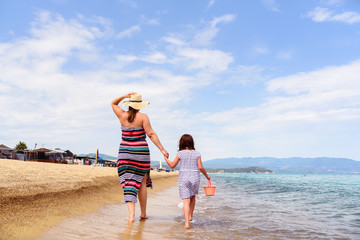 Mother And Little Daughter Walking Along Beautiful Beach 