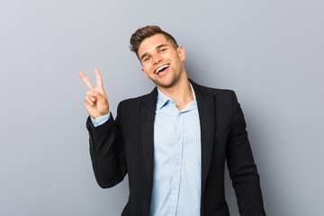 Young handsome caucasian man joyful and carefree showing a peace symbol with fingers.