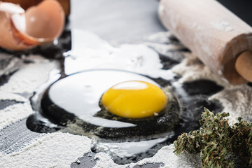 The process of making cannabis pastries. raw broken egg, a rolling pin, flour, and dried marijuana...