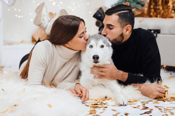 Merry Christmas and Happy New Year. Young couple and a cute dog. Couple spending Christmas eve at...