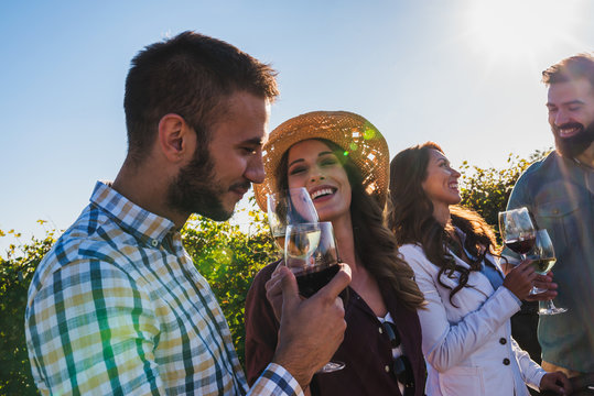 Happy friends having fun drinking wine at winery vineyard - Friendship concept with young people enjoying harvest time together