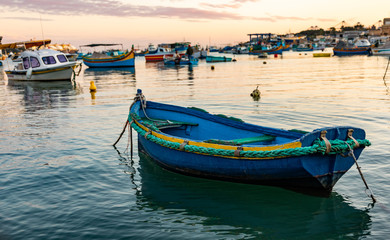 Obraz premium Old colorful fisherman boat in the harbor of Marsaxlokk in Malta on sunset