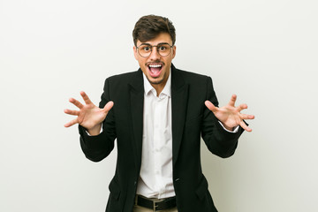 Young business hispanic man celebrating a victory or success, he is surprised and shocked.