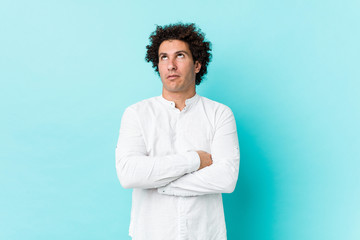 Young curly mature man wearing an elegant shirt tired of a repetitive task.