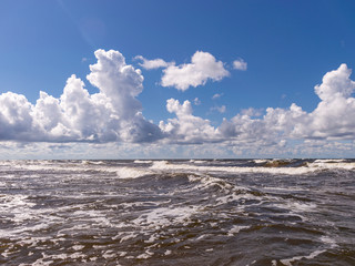 blurred foreground with sparkling waves, clouds and sea in the background