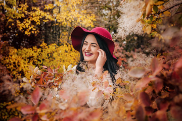 Fototapeta na wymiar Beautiful woman in red hat in autumn garden