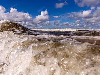 blurred foreground with sparkling waves, clouds and sea in the background