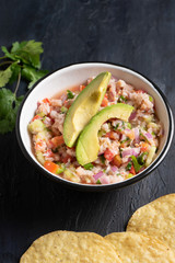 Mexican fish  ceviche with avocado on dark background