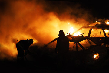 Cars on fire, firefighters work, extinguish a fire. Burning cars, unrest, anti-government, crime. Consequences of the collision. Noise and grain in the image