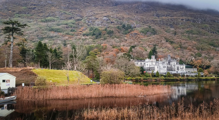 Kylemore Abbey in Connemara, Ireland. Autumn with Lough lake reflections at the bottom of Druchruach mountain. Benedictine monastery castle. 