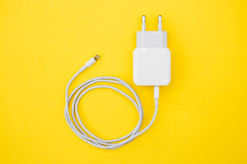 Mobile charger and USB Cable on yellow background. Top view. Copy, empty space for text