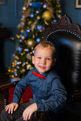Beautiful boy sits on an armchair in a New Year's decor.