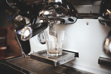 Espresso pouring from coffee machine. Professional coffee brewing.