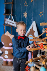 Happy boy in New Year's decor decorate a wooden Christmas tree. New Year 2020.