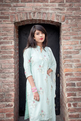 Indian girl in traditional dress stand at the entrance to the house.