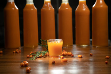 alcoholic cocktail in a shot glass on a totally wooden background: homemade bitter berry tincture with a​​ buckthorn