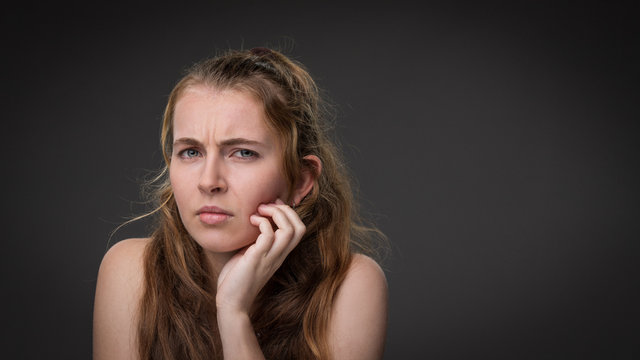A young girl gives a disgusted look isolated against a grey background