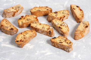 Tasty traditional Italian homemade biscotti or cantuccini cookies with hazelnuts, almonds and walnuts on a light gray background.