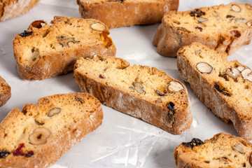 Tasty traditional Italian homemade biscotti or cantuccini cookies with hazelnuts, almonds and walnuts on a light gray background.