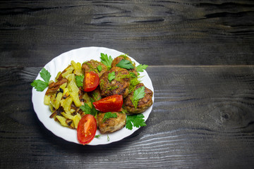 fried potatoes with vegetables and meatballs, top view, selective focus