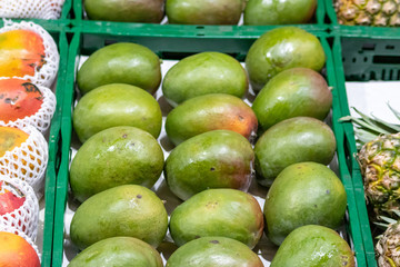 Importiertes Obst in Form frischer vorgereifter Mangos wird an einem Obststand von einem Biobauern...