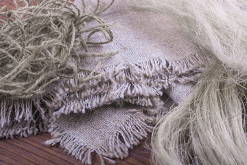 Linen fabric and flax threads on a wooden table close-up.