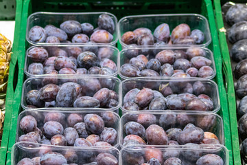 Obststand mit frischen Pflaumen verkauft exotische Früchte für Vegetarier und Veganer und ihre gesunde Ernährung mit frischen Früchten und vitaminreicher Rohkkost
