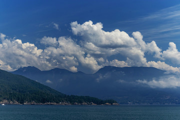 Coastal Pacific mountains as viewed from the Thick white clouds drift over the mountain on the Pacific Ocean, BC, Canada