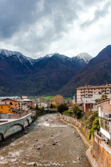 Fototapeta na wymiar Aosta valley, Piedmont, Italy - River view in picturesque Bard town with colorful buildings known for the iconic snow capped peaks as Mont Blanc, Gran Paradiso and ski resort Courmayeur. 