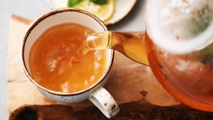 Pouring green tea in cup. Glass tea pot. Hot healthy drink - Powered by Adobe