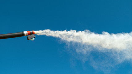 CLOSE UP: White smoke comes blasting out of a black fire extinguisher hose. - obrazy, fototapety, plakaty